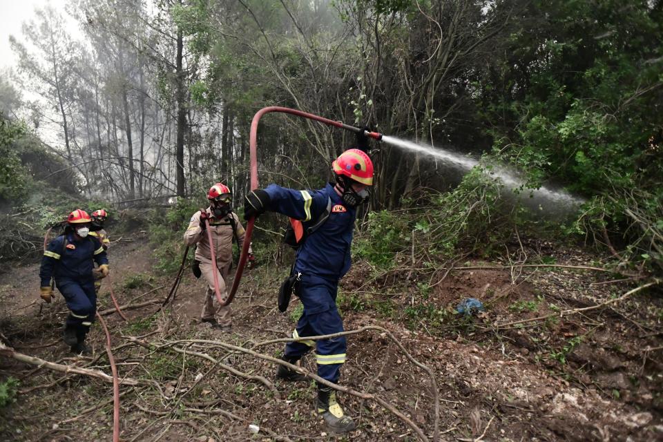 Firefighters operate in Asmini village on Evia island, about 193 kilometers (120 miles) north of Athens, Greece, Sunday, Aug. 8, 2021. Pillars of billowing smoke and ash turned the sky orange and blocked out the sun above Greece's second-largest island Sunday as a days-old wildfire devoured pristine forests and encroached on villages, triggering more evacuation alerts. (AP Photo/Michael Varaklas)