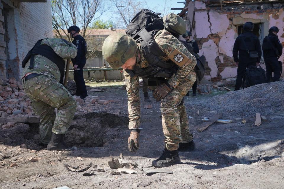 A Ukrainian police officer examines fragments of a guided bomb after a Russian air raid in Kharkiv (AP)