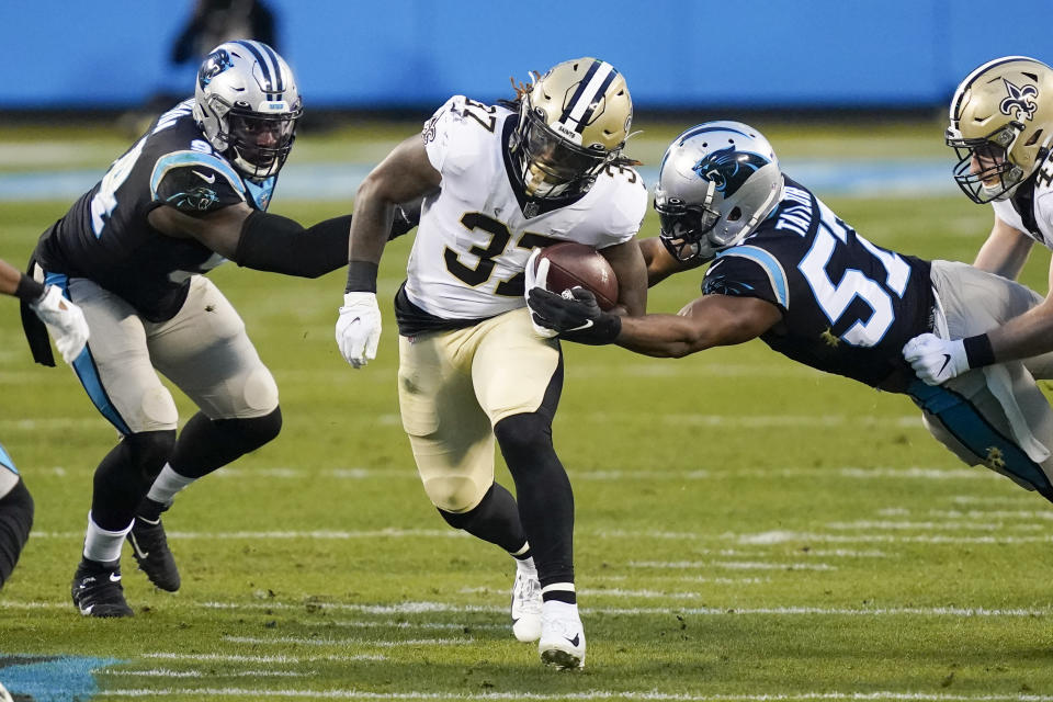New Orleans Saints running back Tony Jones runs between Carolina Panthers defensive end Efe Obada, left, and outside linebacker Adarius Taylor during the first half of an NFL football game Sunday, Jan. 3, 2021, in Charlotte, N.C. (AP Photo/Gerry Broome)