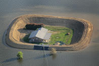 VICKSBURG, MS - MAY 18: A levee protects a home surrounded by floodwater from the Yazoo River May 18, 2011 near Vicksburg, Mississippi. The flooded Mississippi River is forcing the Yazoo River to top its banks where the two meet near Vicksburg causing towns and farms upstream on the Yazoo to flood. The Mississippi River at Vicksburg is expected to crest May 19. Heavy rains have left the ground saturated, rivers swollen, and have caused widespread flooding along the Mississippi River from Illinois to Louisiana. (Photo by Scott Olson/Getty Images)