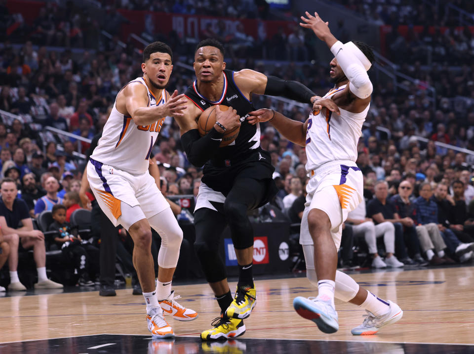 Guard Los Angeles Clippers Russell Westbrook melaju ke keranjang antara guard Phoenix Suns Devin Booker dan Josh Okogie selama Game 4 dari seri playoff NBA putaran pertama mereka di Crypto.com Arena di Los Angeles pada 22 April 2023. (Harry How/Getty Images )