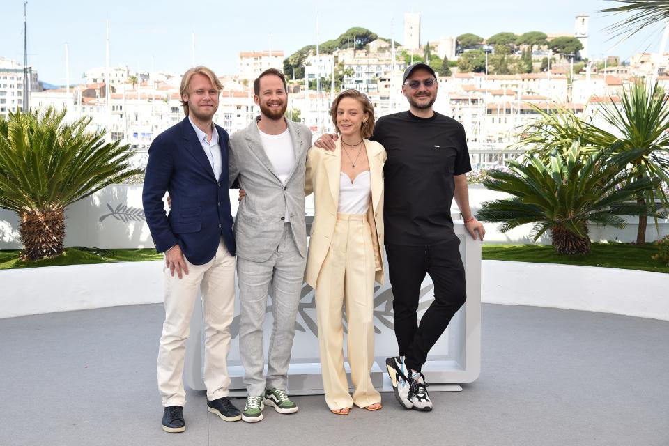 Four people pose with Cannes, France in the background.