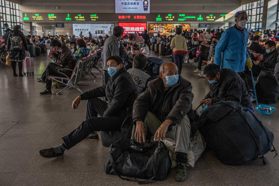 Passengers wearing protective face masks use their mobile phones as they wait with their luggage at the Beijing West railway station amid the coronavirus pandemic in Beijing. Source: AAP