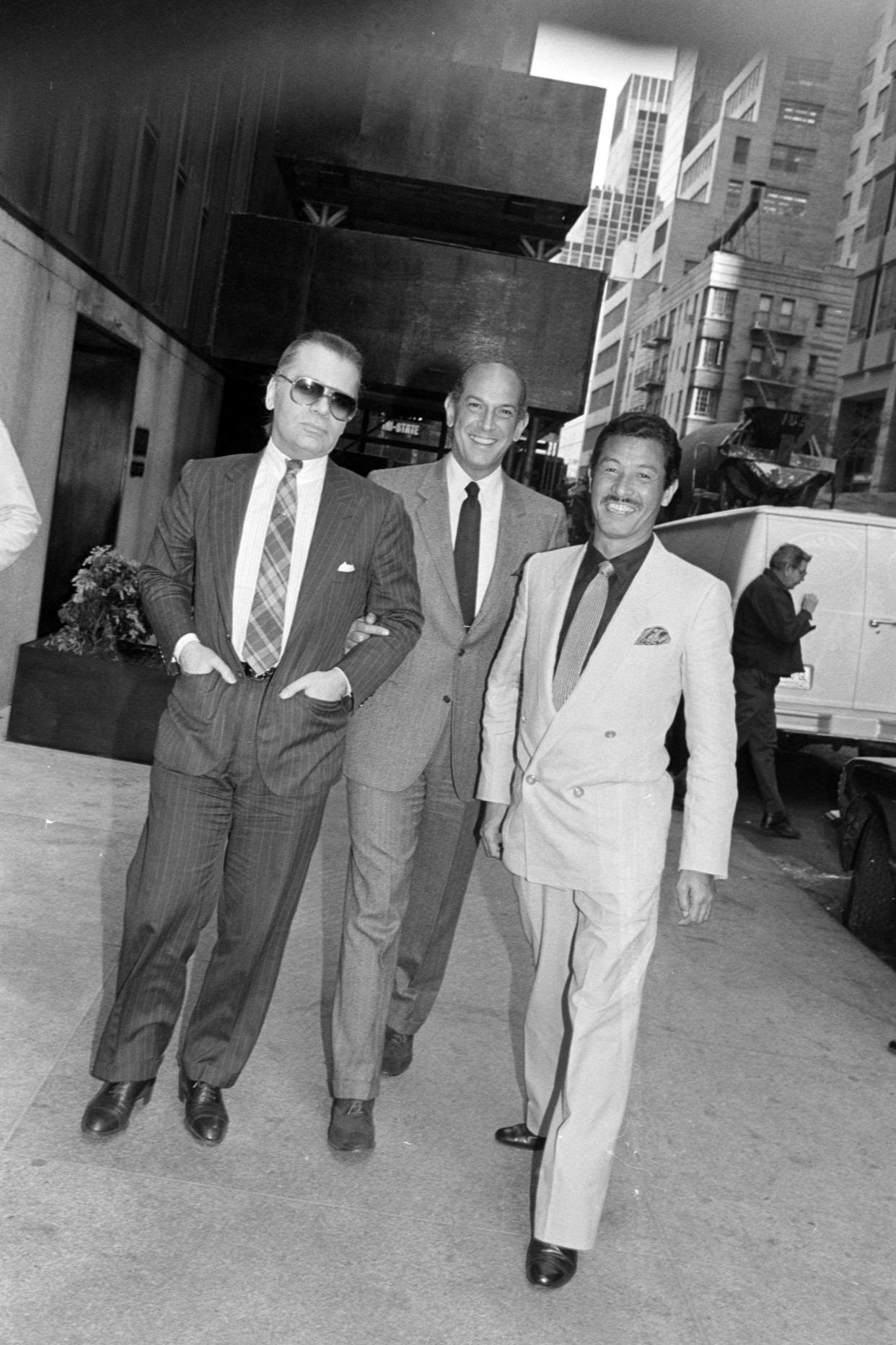 Designers Karl Lagerfeld, Oscar de la Renta and Issey Miyake pose for a portrait outside the Four Seasons Hotel in New York City on April 12, 1984. - Credit: WWD