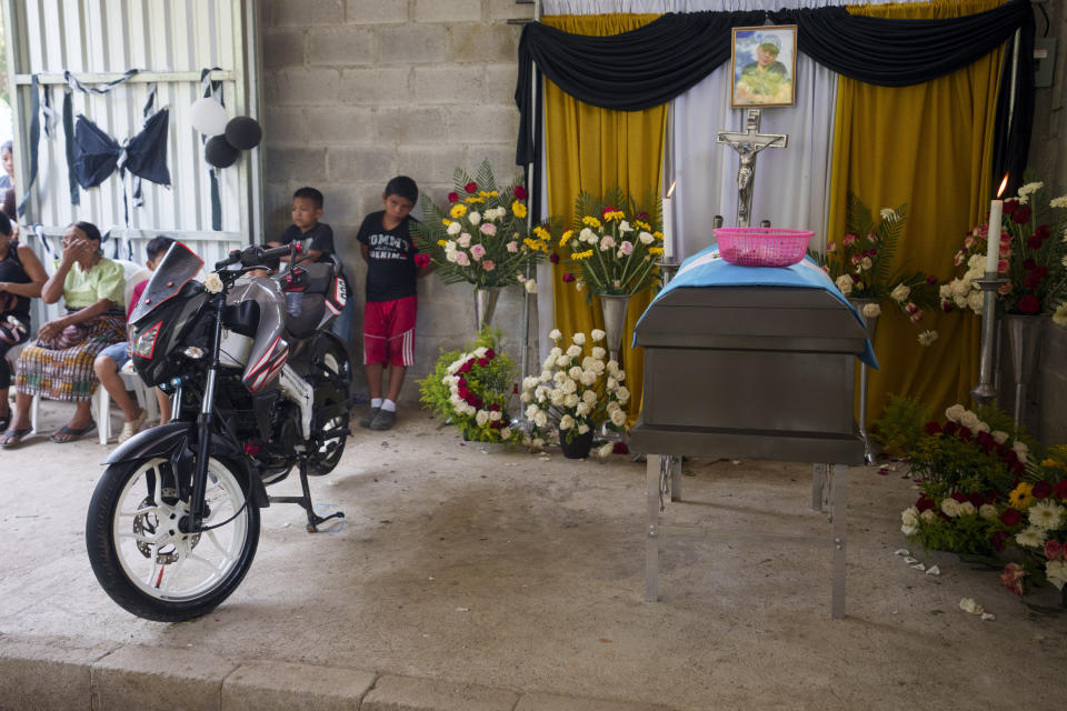 Vecinos asisten al velorio del migrante guatemalteco Francisco Rojché, con su motocicleta aparcada al lado de su ataúd, en su casa en Chicacao, Guatemala, el miércoles 12 de abril de 2023. Rojché y su tío Miguel murieron en un incendio cuando estaba encerrados en un centro de detención de migrantes mexicano en Ciudad Juárez. (AP Foto/Moisés Castillo)