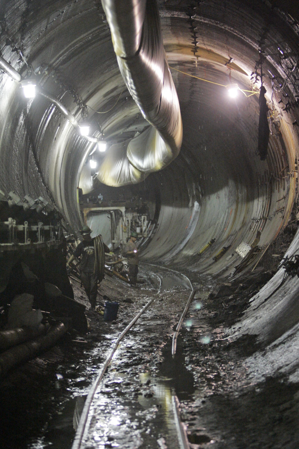 FILE- In this July 17, 2008 file photo, a couple of sandhogs work in the East bound tunnel of the Metropolitan Transportation Authority's East Side Access project in New York. On Monday, July 23, 2012 the last of the 200-ton tunnel boring machines finished its mission and went quiet. The seven machine fleet dug 13 miles of new train tubes deep beneath New York City, boring through bedrock and creating 16 new tunnels in 4 ½ years of digging. (AP Photo/Mary Altaffer, File)