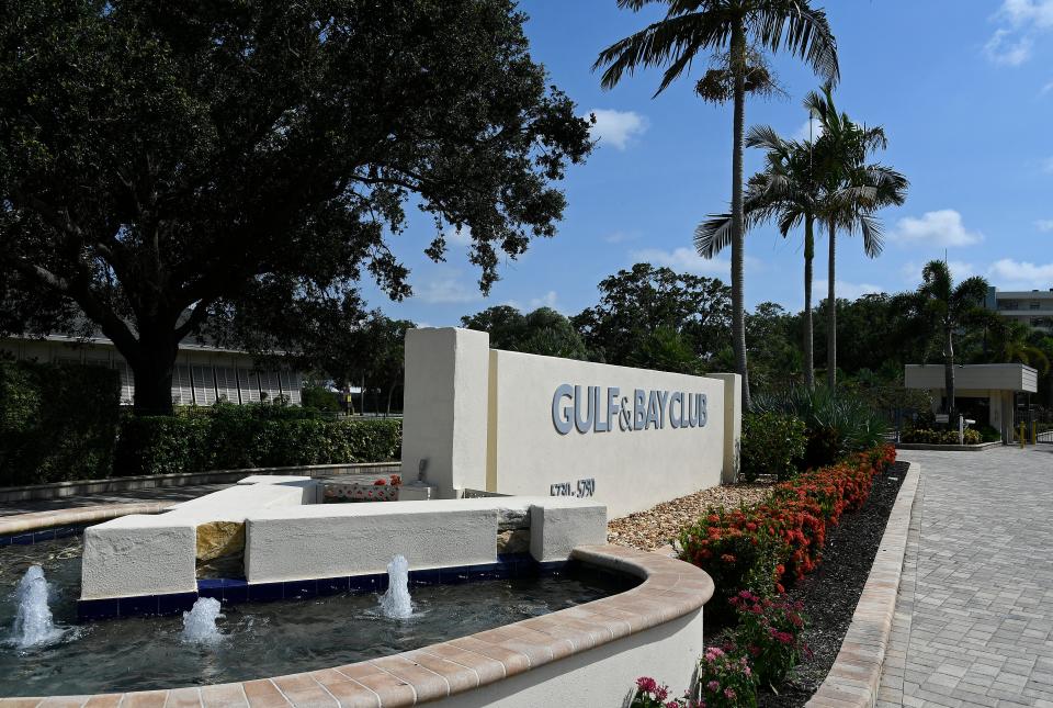 The divided entrance to Gulf & Bay Club on Midnight Pass Road has pretty, small water fountains in front of the signage wall, paver roadways, and ample tropical shrubbery – a preview of more to come inside.