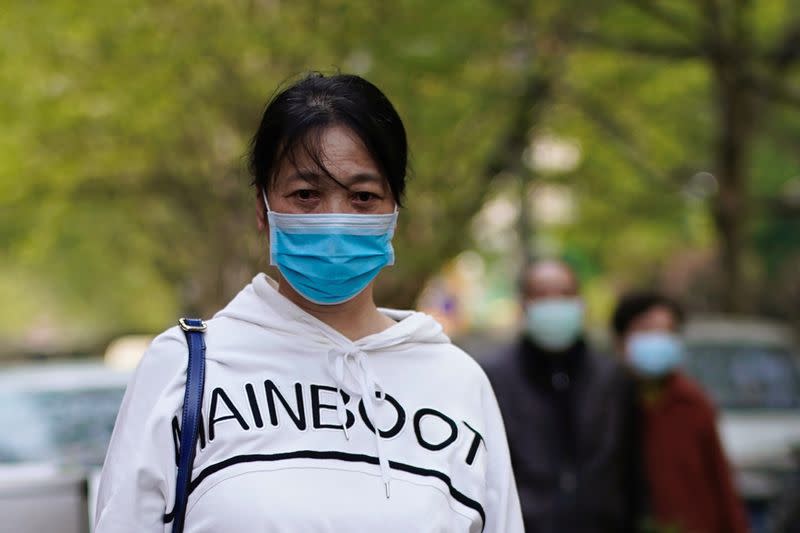 Woman wearing a face mask observes a moment of silence on a street in Wuhan