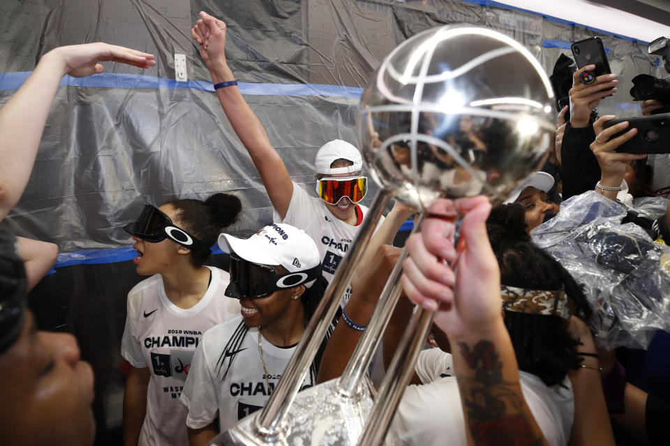 Washington Mystics forward Elena Delle Donne, back center, and others celebrate with the trophy in the locker room after Game 5 of basketball's WNBA Finals against the Connecticut Sun, Thursday, Oct. 10, 2019, in Washington. (AP Photo/Alex Brandon)