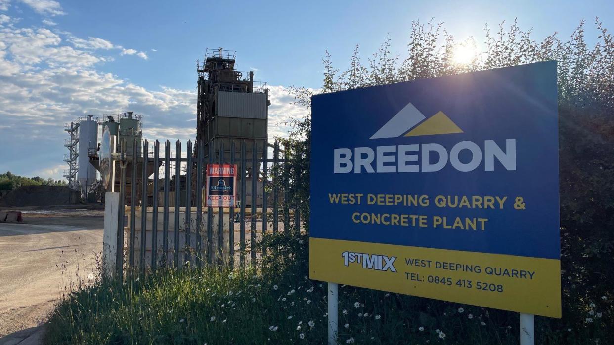 The entrance to a quarry at West Deeping, with a "Breedon" sign in the foreground and tall industrial buildings in the background.