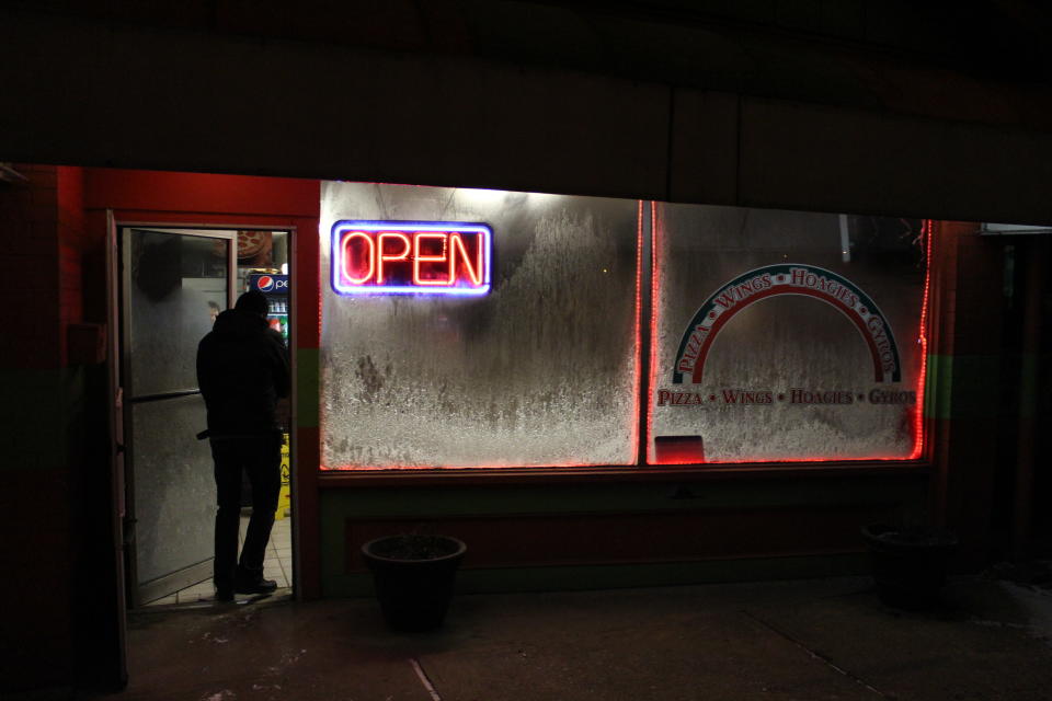 Pizza deliveryman Taras Sushko walks through the ice-crusted door of Nicco's Pizza in Coraopolis, Pa., on Monday, Jan. 6, 2014. As dangerously frigid air swept through this hard-luck Pennsylvania town on Monday night and early Tuesday morning, the few people who ventured outside needed something—mostly gambling, a drink or cigarettes. (AP Photo/Jesse Washington)