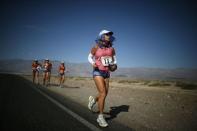 Shannon Farar-Griefer, 52, of Hidden Hills, California (R) runs away from her team after stopping to drink water as she competes in the Badwater Ultramarathon in Death Valley National Park, California in this July 15, 2013 file photo. An ultramarathon involves a combination of running and walking further than the traditional marathon of 26.2 miles (42.2 kilometres). Though most ultras cover distances of either 50 or 100 miles, many are much longer. For the ultramarathoner, it is all about running for joy, setting personal goals and trying to overcome every obstacle faced. To match ATHLETICS-ULTRAMARATHONS/ REUTERS/Lucy Nicholson/Files (UNITED STATES - Tags: SPORT ATHLETICS)