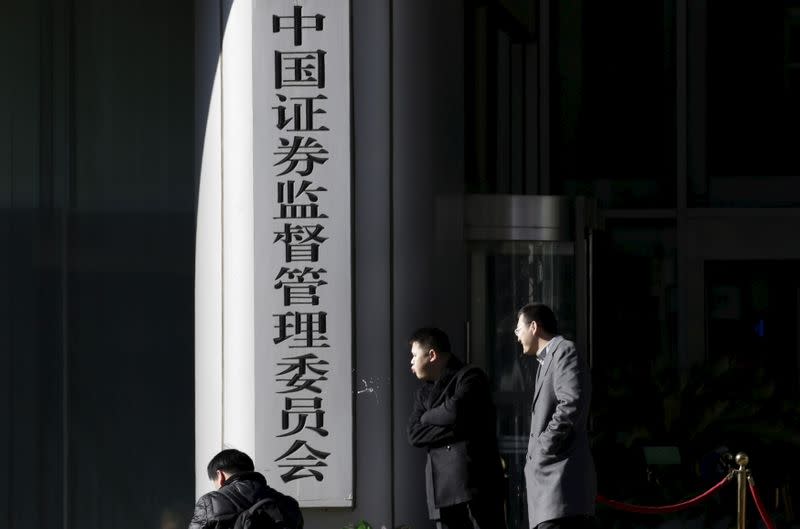 Men rest outside the headquarters building of China Securities Regulatory Commission in Beijing