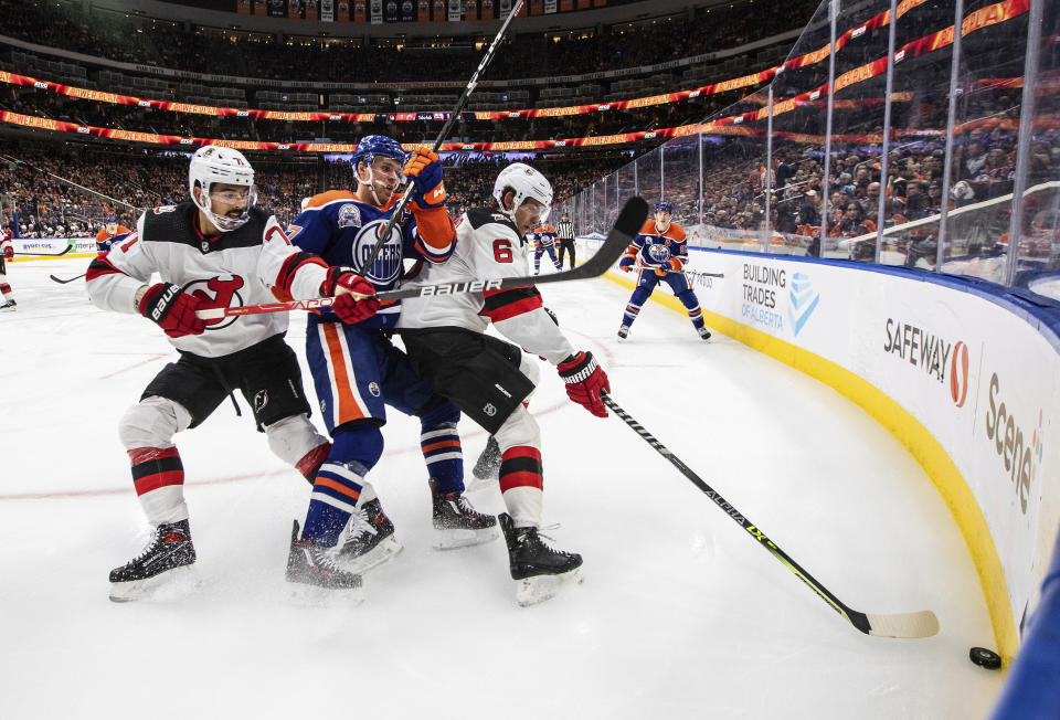 New Jersey Devils' Jonas Siegenthaler (71) and John Marino (6) battle for the puck against Edmonton Oilers' Connor McDavid (97) during second-period NHL hockey game action in Edmonton, Alberta, Thursday, Nov. 3, 2022. (Jason Franson/The Canadian Press via AP)