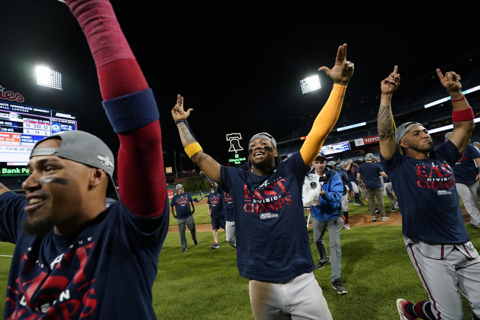 Atlanta Braves' Orlando Arcia, from left, Ronald Acuna Jr. and Eddie Rosario celebrate after clinching their sixth consecutive NL East title by defeating the Philadelphia Phillies in a baseball game, Wednesday, Sept. 13, 2023, in Philadelphia. (AP Photo/Matt Slocum)