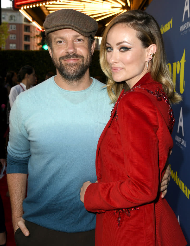 Jason Sudeikis in a casual sweater and cap, and Olivia Wilde in a fashionable coat, pose together at a Booksmart event