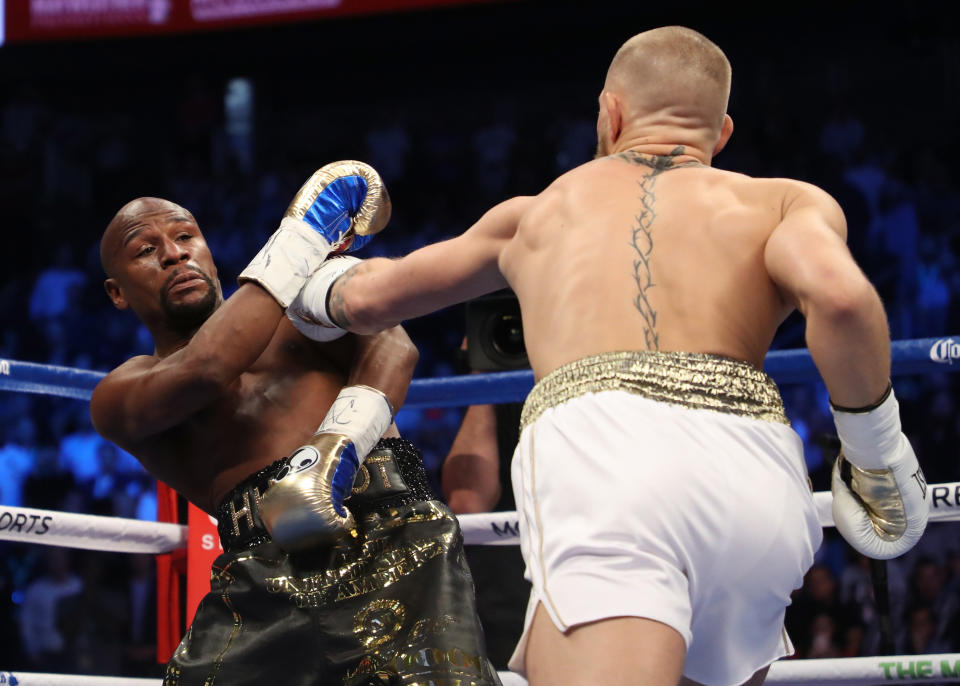 LAS VEGAS, NV - AUGUST 26:  (R-L) Conor McGregor throws a punch at Floyd Mayweather Jr. during their super welterweight boxing match on August 26, 2017 at T-Mobile Arena in Las Vegas, Nevada.  (Photo by Christian Petersen/Getty Images)