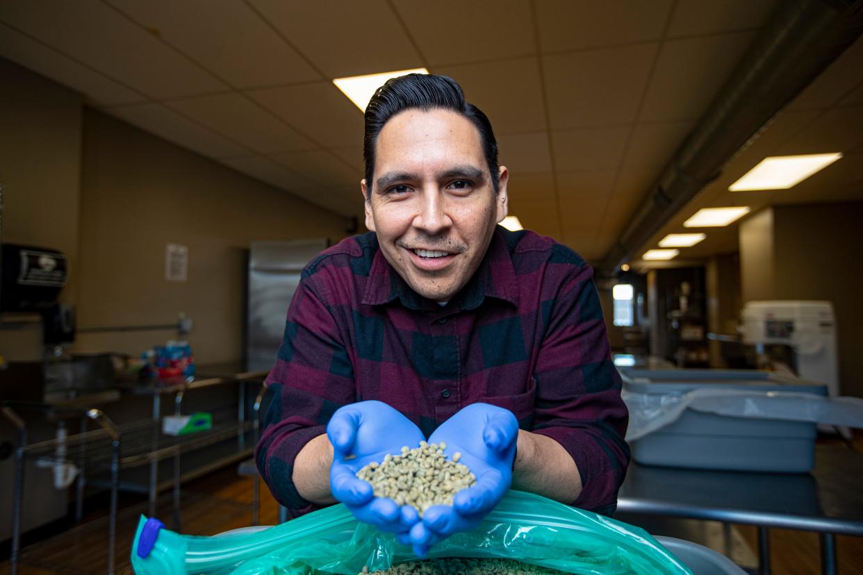 Jaime Perez poses for a photo with raw coffee beans on Friday, Feb. 10, 2023, at Rockford City Market in Rockford.