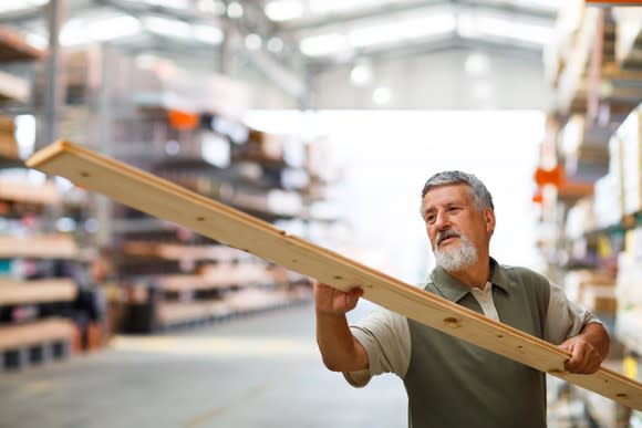 A shopper inspects a piece of lumber at a home improvement warehouse.