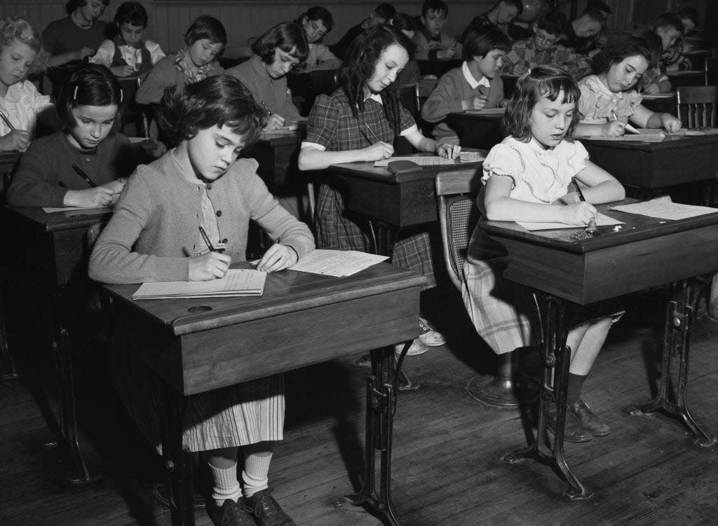 black and white photo of children at school desks in the 1940s