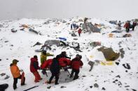 Rescuers use a makeshift stretcher to carry an injured person on April 25, 2015 after an avalanche triggered by an earthquake flattened parts of Everest Base Camp