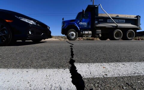 Vehicles drive over a crack on Highway 178 south of Trona, after a 6.4-magnitude earthquake hit in Ridgecrest, California - Credit: AFP