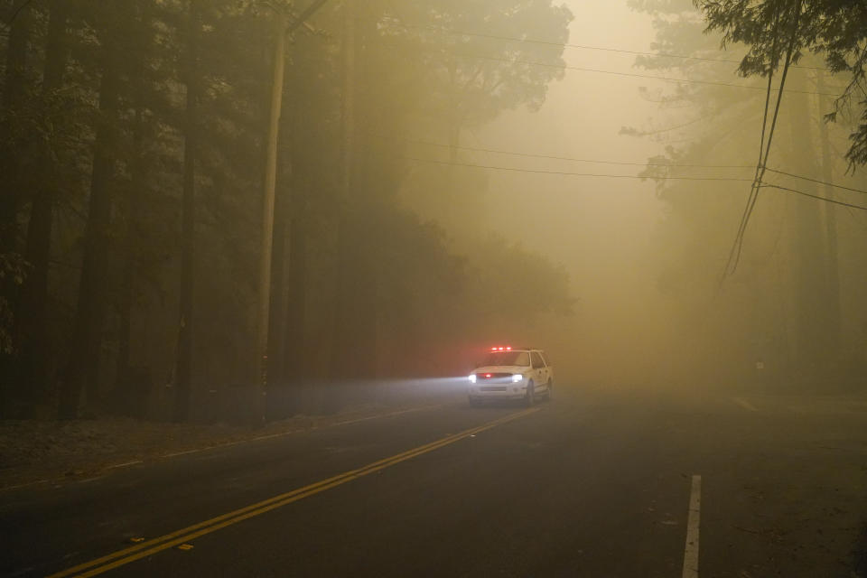 An emergency vehicle goes along a smoke- filled mountain road as crews continue to fight the CZU August Lightning Complex fire Saturday, Aug. 22, 2020, in Boulder Creek, Calif. (AP Photo/Marcio Jose Sanchez)