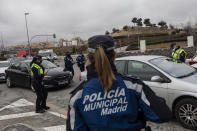 A police officer checks a driver's documents at a checkpoint on the outskirts of Madrid, Spain, Monday, Jan. 25, 2021. With several regions reporting Friday new daily records of infections, some regional governments are toughening their response. The central Madrid region, home to 6.6 million, brought its curfew from midnight to 10 p.m. starting on Monday, and ordered shop, bar and restaurant closures at 9 p.m. the latest. (AP Photo/Bernat Armangue)
