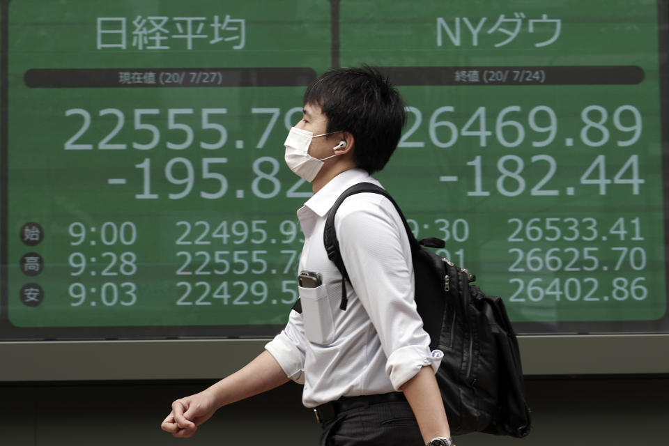 A man walks past an electronic stock board showing Japan's Nikkei 225 and New York Dow indexes at a securities firm in Tokyo Monday, July 27, 2020. Asian stock markets were mixed Monday amid U.S.-China tension and concern a recovery from the coronavirus pandemic might be weakening. (AP Photo/Eugene Hoshiko)