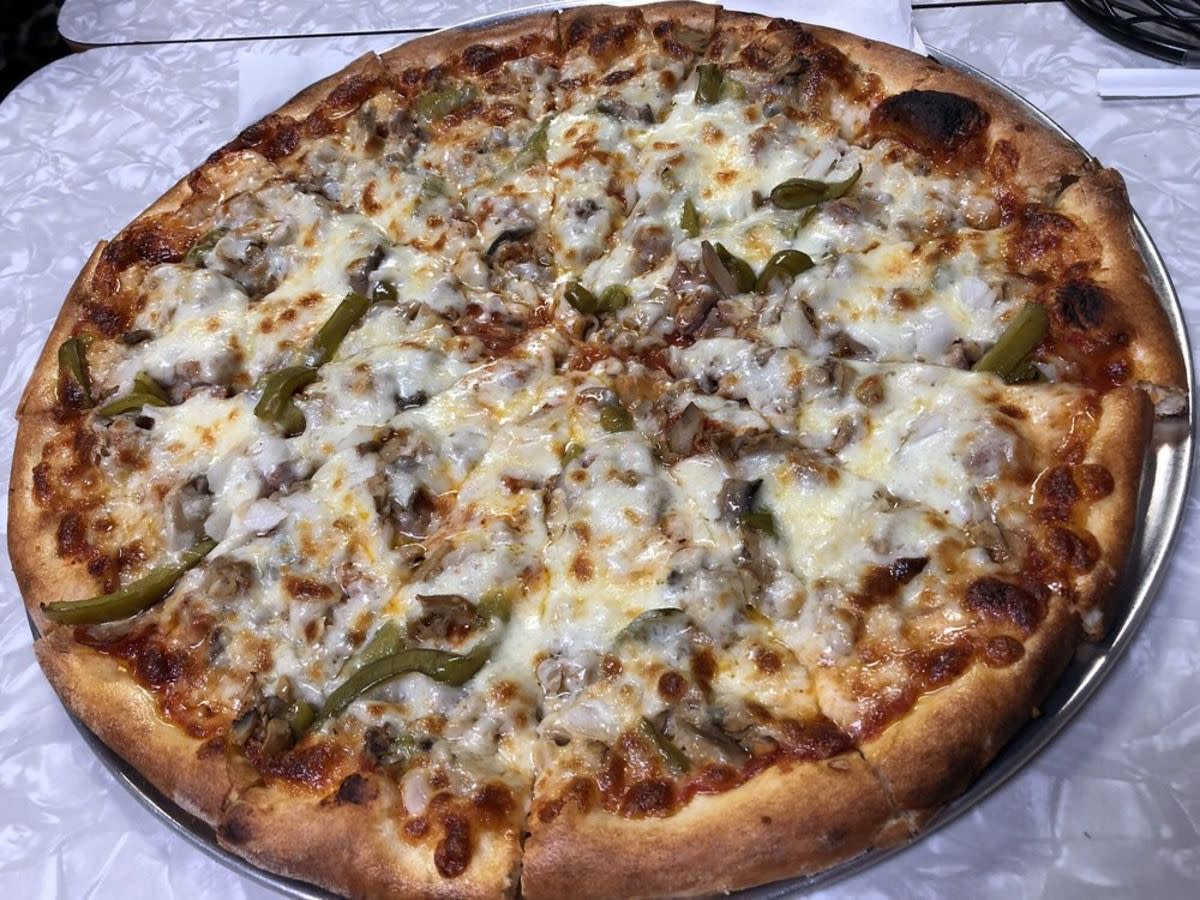 Large Special Pizza with homemade sausage, pepperoni, mushroom, onion and green peppers on pizza tray, Pizza-A-Go-Go, St. Louis, on a shiny swirly white table