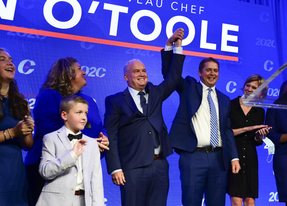 Newly elected Conservative Leader Erin O'Toole, center, has his hand hoisted by outgoing leader Andrew Scheer as he stands his wife and children after delivering his winning speech following the Conservative party of Canada 2020 Leadership Election in Ottawa on Monday, Aug. 24, 2020. (Sean Kilpatrick/The Canadian Press via AP)