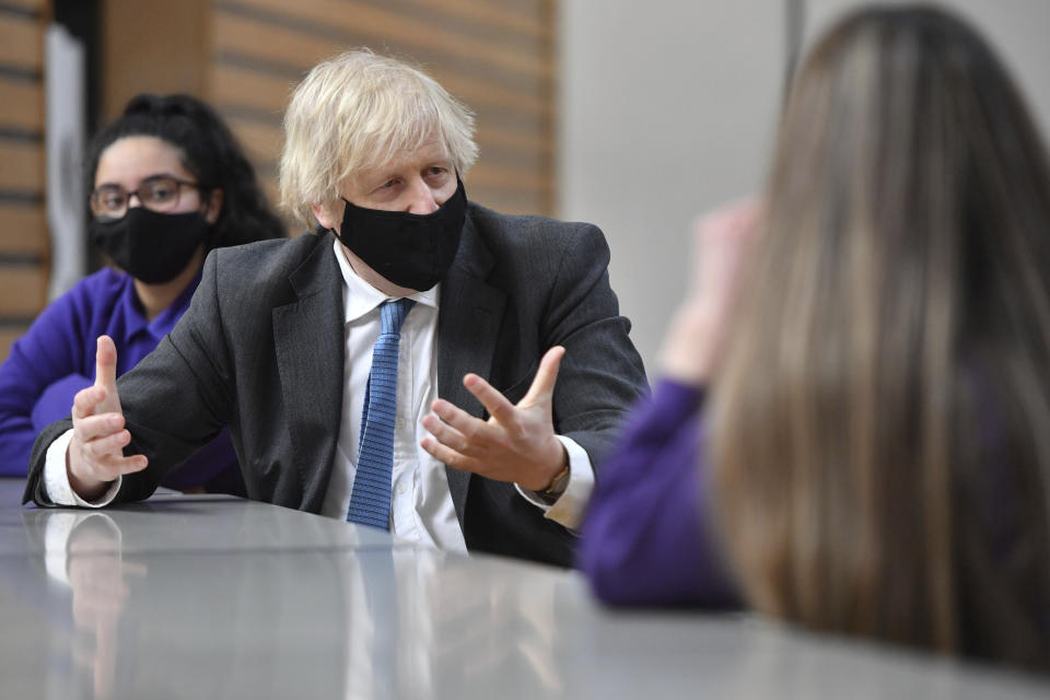 Britain's Prime Minister Boris Johnson meets with Year 11 students in the canteen during a visit to Accrington Academy in Accrington, England, Thursday, Feb. 25, 2021, as they prepare for the return of all pupils on March 8. (Anthony Devlin/Pool Photo via AP)