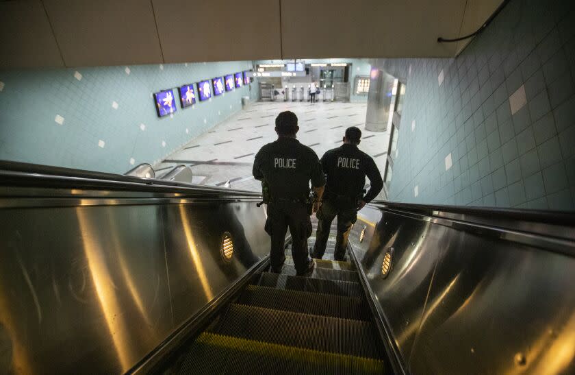 HOLLYWOOD, CA - JUNE 25: LAPD officers E. Rosales, left, and D. Castro, patrol the Metro Red Line Hollywood/Highland Metro Station as tourists pass by Thursday, June 25, 2020 in Hollywood, CA. The Metro Board of Directors held a meeting Thursday where the agenda included the consideration of appointing a committee to develop plans for replacing armed transit safety officers with ``smarter and more effective methods of providing public safety.'' Metro security is staffed by multiple agencies, including the L.A. County Sheriff's Department and L.A. and Long Beach police departments, transit security guards and contract security workers. (Allen J. Schaben / Los Angeles Times)