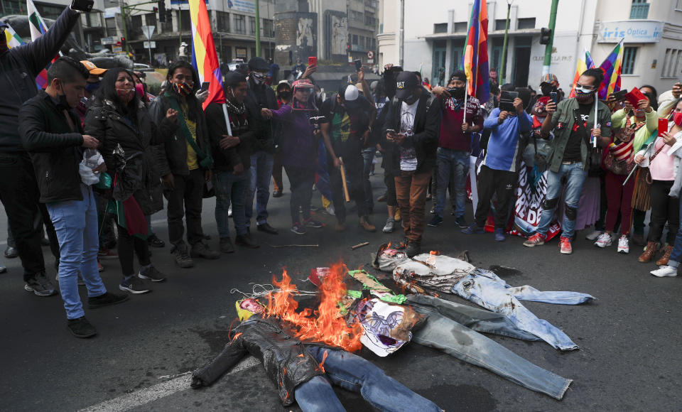 Manifestantes bolivianos queman figuras que representan a la presidenta interina Jeanine Áñez, al ministro de Interior, Arturo Murillo y al de Educación, Víctor Hugo Cárdenas, durante una protesta en La Paz, Bolivia, el martes 14 de julio de 2020. (AP Foto/Juan Karita)