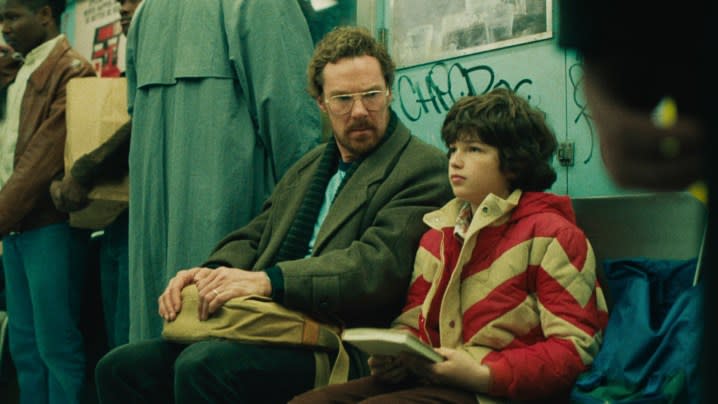 A man and a boy sit on a subway train in Eric.