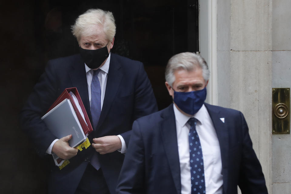 Britain's Prime Minister Boris Johnson, left, leaves Downing Street with a member of security staff to attend the weekly session of Prime Ministers Questions at Parliament in London, Wednesday, Oct. 21, 2020. The European Union is taking a defiant tone as the standoff over resuming post-Brexit trade negotiations with the United Kingdom continues. The bloc told London Wednesday that "you cannot have your cake and eat it too." (AP Photo/Frank Augstein)