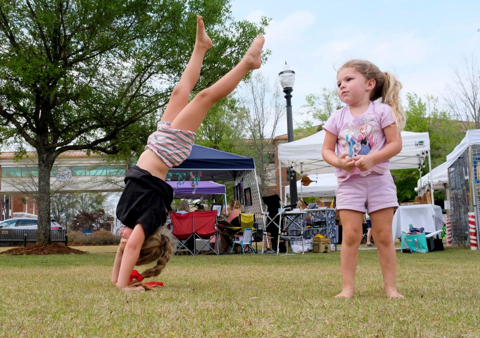 Everleigh Barr does a handstand as she plays with her sister Emileigh at the Druid City Arts Festival in Government Plaza on March 31, 2023.