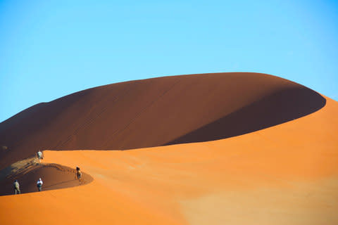 November: Ian Yates's photograph of travellers scaling a golden dune in Namibia - Credit: Ian Yates