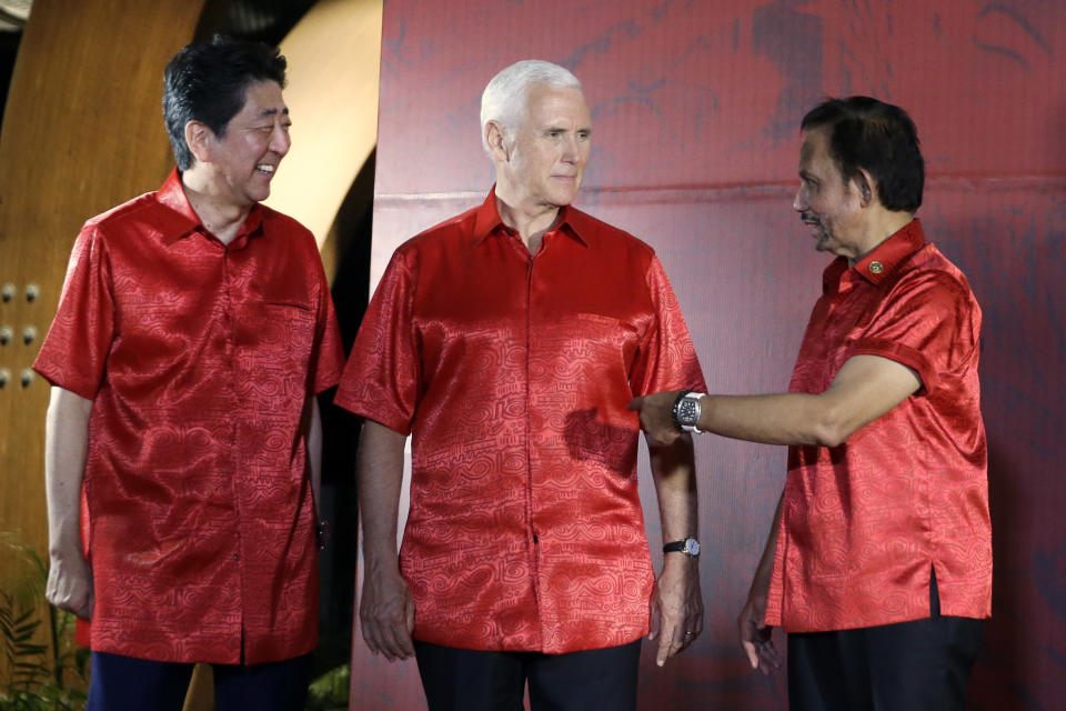 From left, Japanese Prime Minister Shinzo Abe, U.S. Vice President Mike Pence and Brunei's Sultan Hassanal Bolkiah talk before a family photo with leaders and their spouses during the APEC Economic Leaders Meeting summit in Port Moresby, Papua New Guinea, Saturday, Nov. 17, 2018. (AP Photo/Mark Schiefelbein)