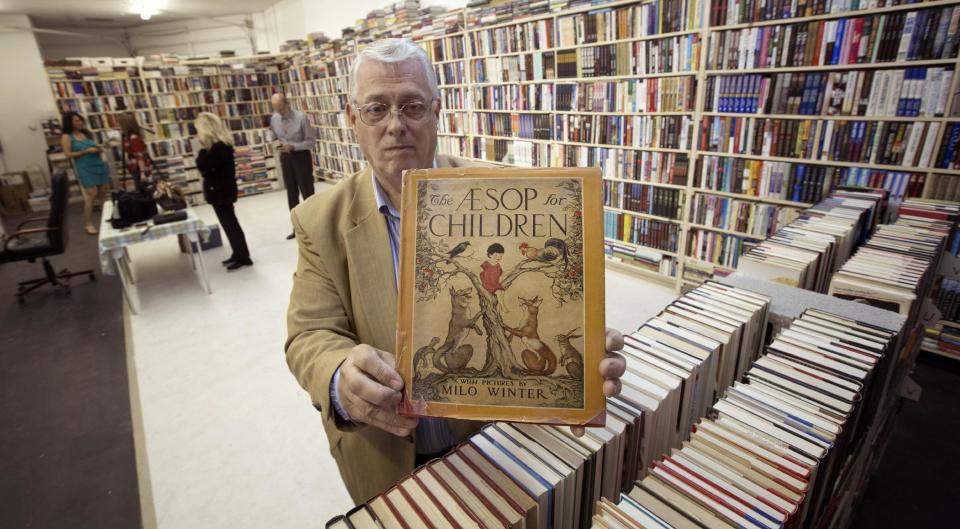 In this Friday, Oct. 19, 2012 photo, memorabilia collector Ken Kallin displays one of his antique books that will be sold at auction in Oakland Park, Fla.  Three decades ago, Kallin began amassing 120,000 pieces in a memorabilia collection that includes photographs signed by Muhammad Ali and Neil Armstrong along with rare books and trading cards. By the end of Saturday, Oct. 27, 2012 he's hoping to have gotten rid of nearly all of it _ at an auction to benefit his daughter, who suffers from a rare autoimmune disease that makes her bones dangerously brittle and causes her body's defenses to attack her own blood vessels.  (AP Photo/J Pat Carter)