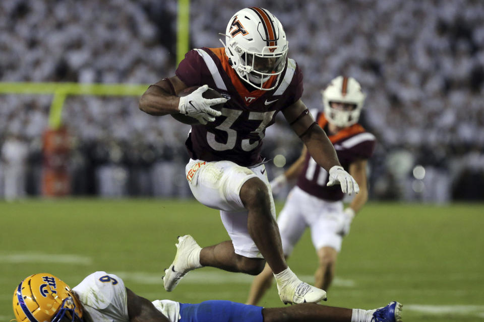 Virginia Tech running back Bhayshul Tuten (33) jumps over Pittsburgh defender A.J. Woods (9) for a touchdown during the first halfof an NCAA college football game Saturday, Sept. 30, 2023, in Blacksburg, Va. (Matt Gentry/The Roanoke Times via AP)