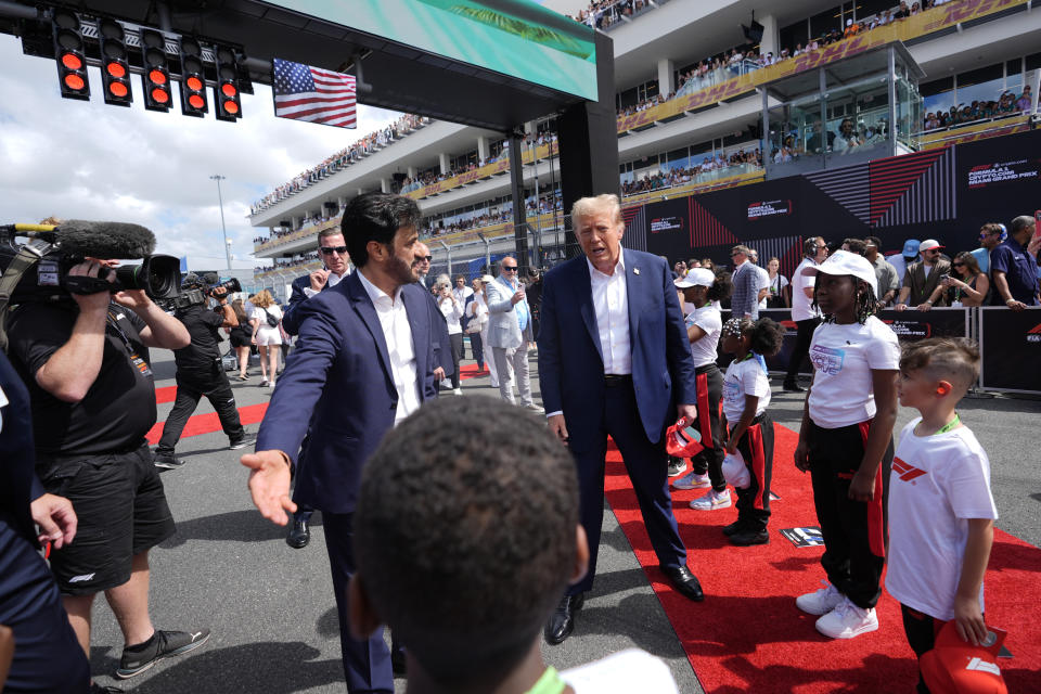 Republican presidential candidate, former President Donald Trump, center, walks along the grid before the Miami Formula One Grand Prix auto race, Sunday, May 5, 2024, in Miami Gardens, Fla. With Trump is FIA President Mohammed Ben Sulayem, left. (AP Photo/Rebecca Blackwell)