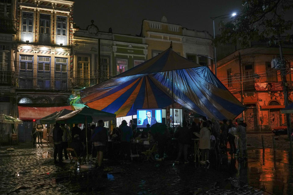 People watch at a square as Brazilian President Jair Bolsonaro speaks during a presidential debate, in Rio de Janeiro on Thursday, Sept. 29, 2022. Brazil's general elections are scheduled for Sunday. (AP Photo/Matias Delacroix)