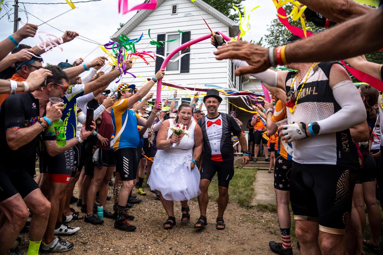 RAGBRAI riders Jamie and Joe Stacey walk hand-in-hand after their wedding at the Iowa Craft Beer Tent on Tuesday, July 25, 2023, near Luther.