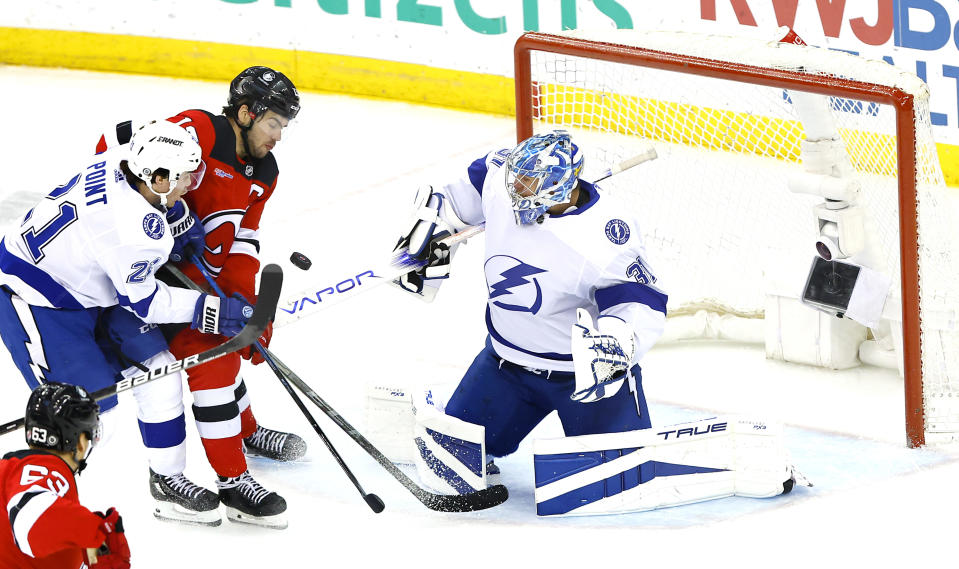 Tampa Bay Lightning goaltender Jonas Johansson (31) and center Brayden Point (21) defend against New Jersey Devils center Nico Hischier during the third period of an NHL hockey game, Sunday, Feb. 25, 2024, in Newark, N.J. The Tampa Bay Lightning won 4-1. (AP Photo/Noah K. Murray)
