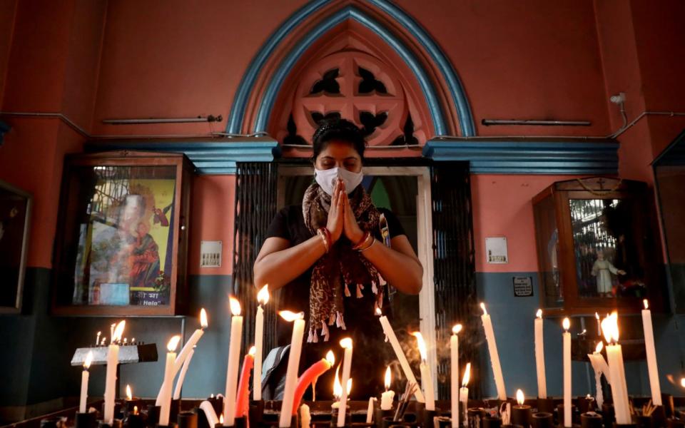 A worshipper wearing a protective face mask prays at a church during Good Friday, amidst the spread of the coronavirus - REUTERS/Rupak De Chowdhuri 