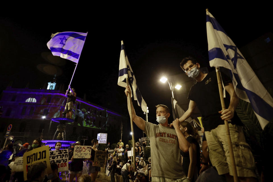 Israeli protesters wave flags during a demonstration against Israeli Prime Minister Benjamin Netanyahu outside the Prime Minister's residence in Jerusalem, Saturday, Sept. 12, 2020. (AP Photo/Sebastian Scheiner)