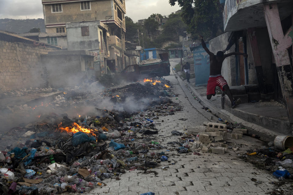 A man jumps over loose bricks forming part of a barricade, a block away from the front lines that divide gang-controlled territories in the Bel Air neighborhood of Port-au-Prince, Haiti, Tuesday, Oct. 5, 2021. The gangs tightening grip on Haitian society is threatening the country's social fabric and its fragile, anemic economy. (AP Photo/Rodrigo Abd)