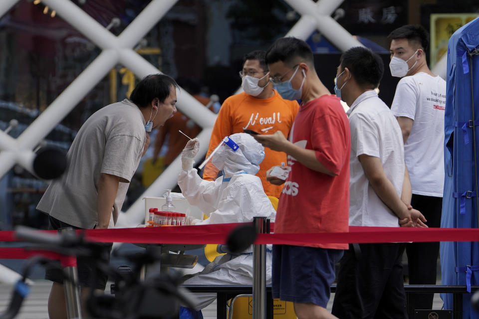 Residents get swabbed during mass COVID-19 testing in the Chaoyang district in Beijing, Tuesday, June 14, 2022. Authorities ordered another round of three days of mass testing for residents in the Chaoyang district following the detection of hundreds coronavirus cases linked to a nightclub. (AP Photo/Andy Wong)