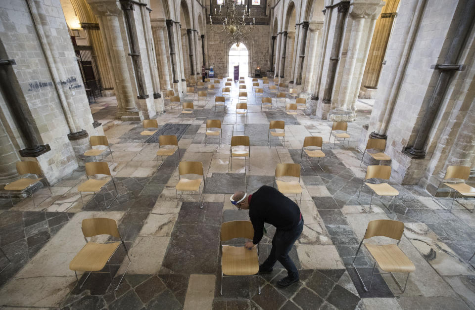 Senior Verger Luke Marshall cleans chairs that have be positioned to allow for social distancing, at Chichester Cathedral as they prepare to reopen for public worship on July 5, as further coronavirus lockdown restrictions are lifted in England, in Chichester, England, Thursday July 2, 2020. (Andrew Matthews/PA via AP)